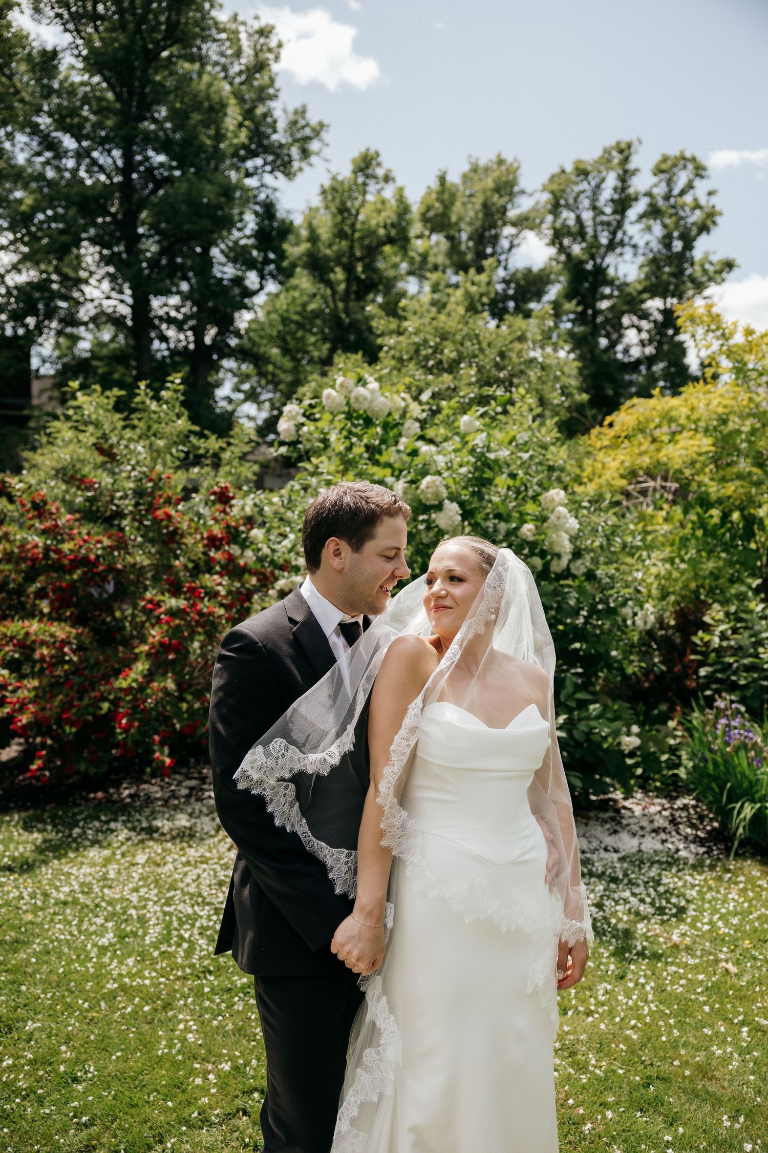 A joyful wedding moment captured in a sunlit garden filled with wildflowers.