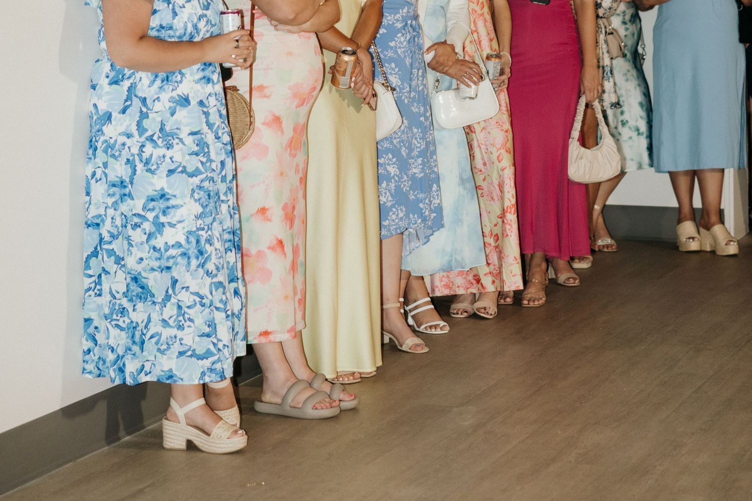 Row of colorful floral dresses and skirts at formal event.