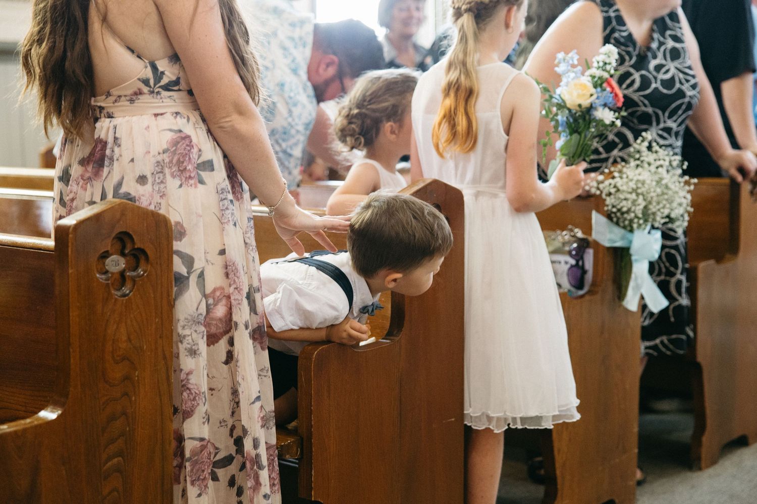 Wedding guests seated in wooden church pews during a ceremony.