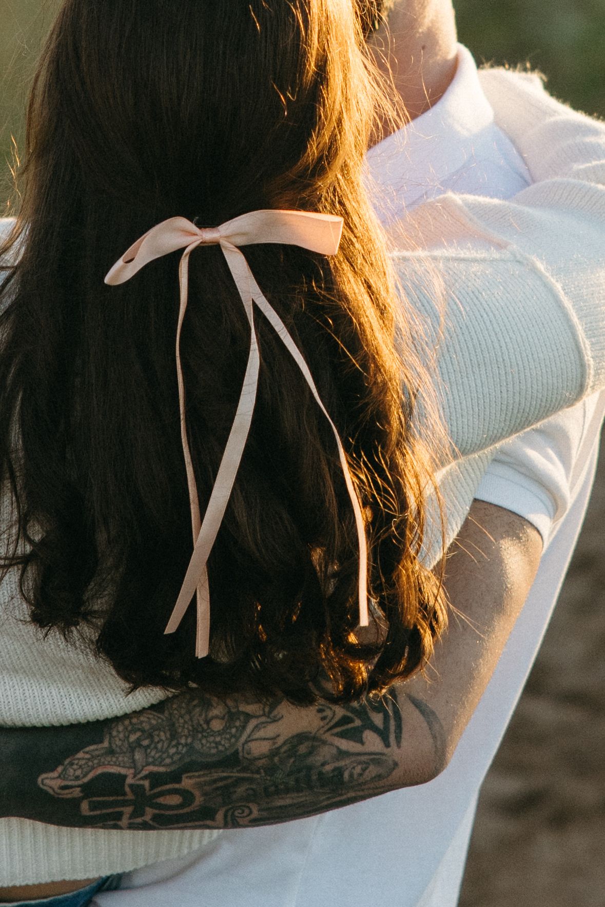 Close-up details of long hair with white ribbon against cream sweater.