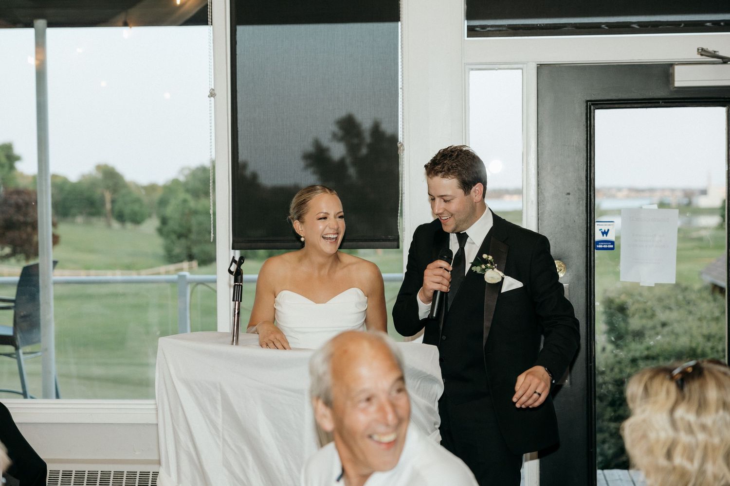 Wedding reception speech brings laughter to guests seated at head table.