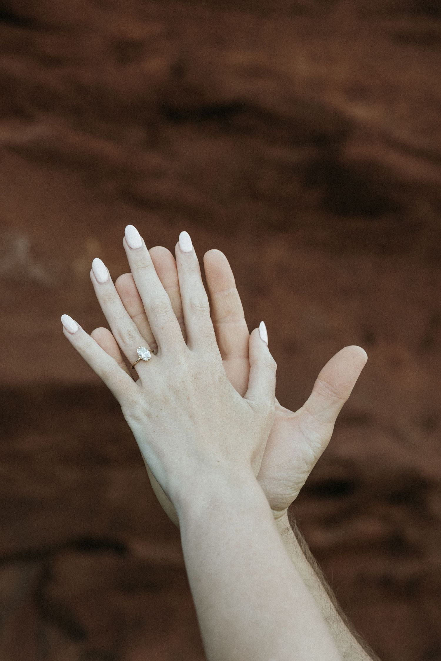 Close-up of hands reaching and touching against a dark background.