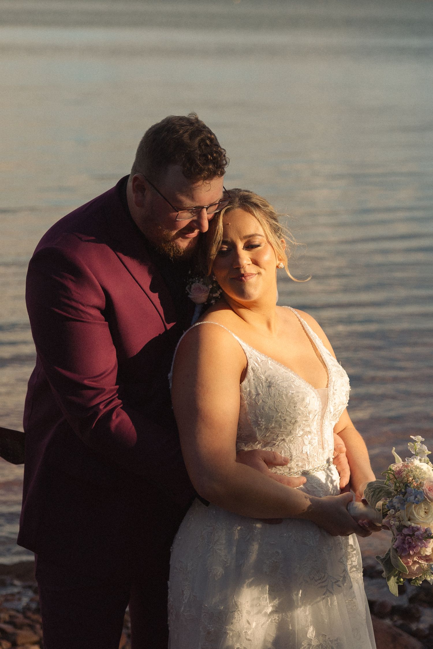 Intimate beach wedding portrait at sunset with warm golden light.