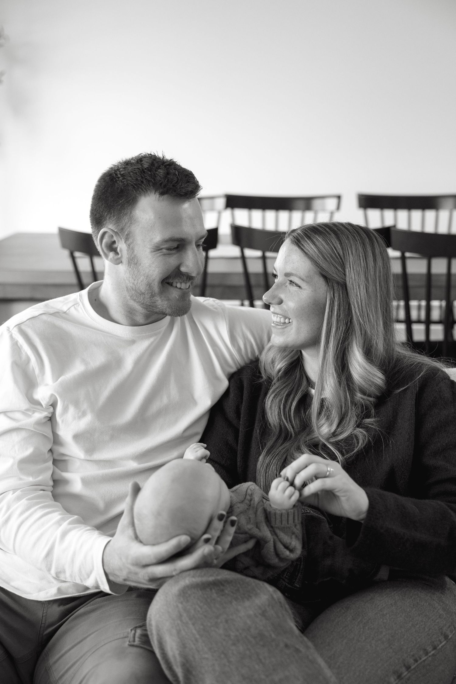 Couple relaxing together on a couch in casual attire sharing a tender moment.