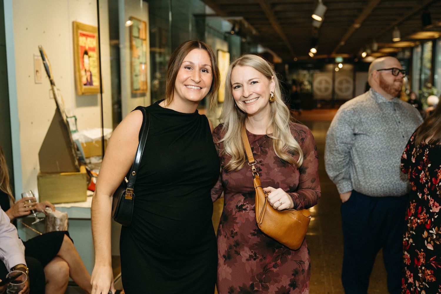 Friends smiling and posing together at a celebratory event in formal attire.