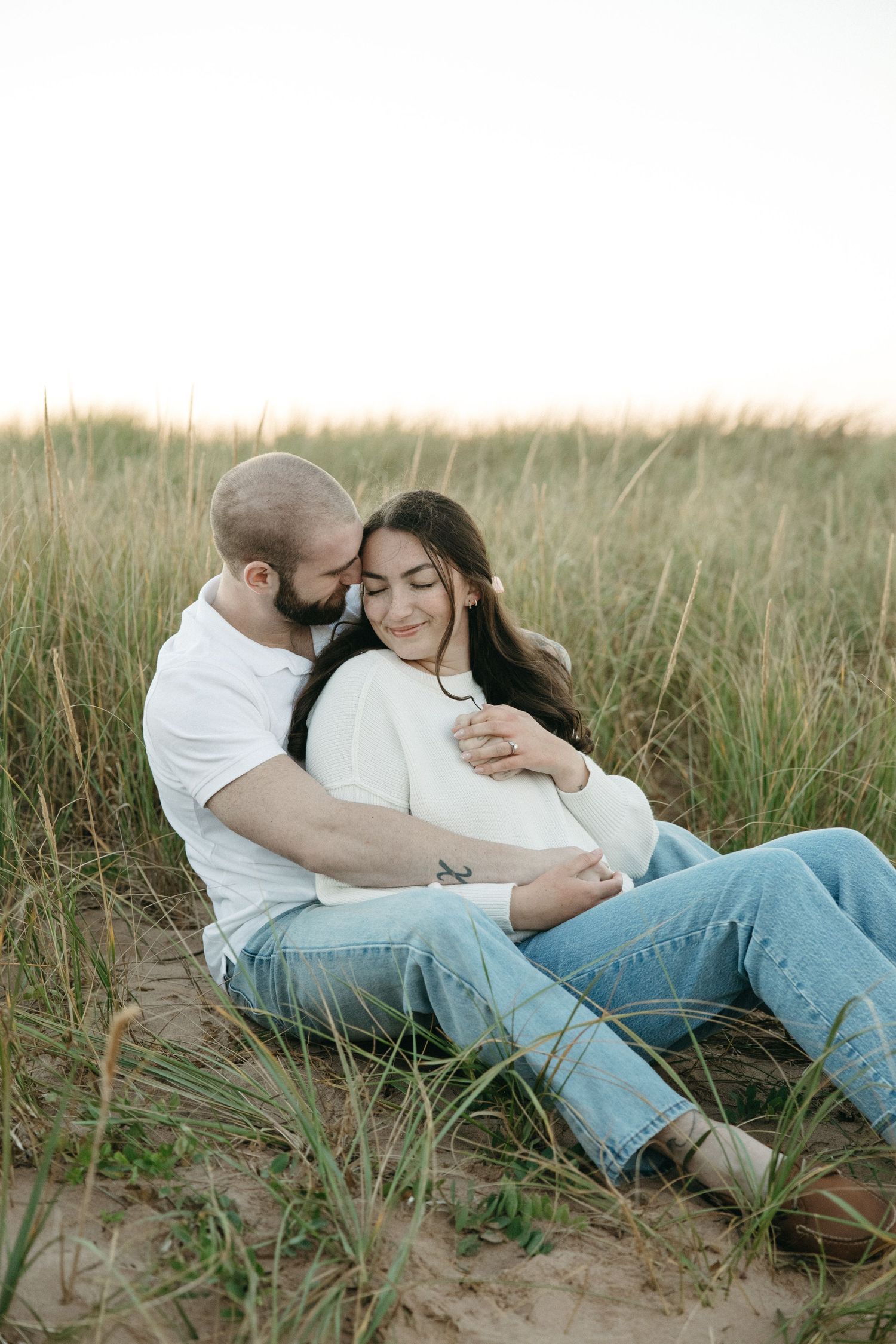 Romantic couple lying together among coastal dunes and beach grass.
