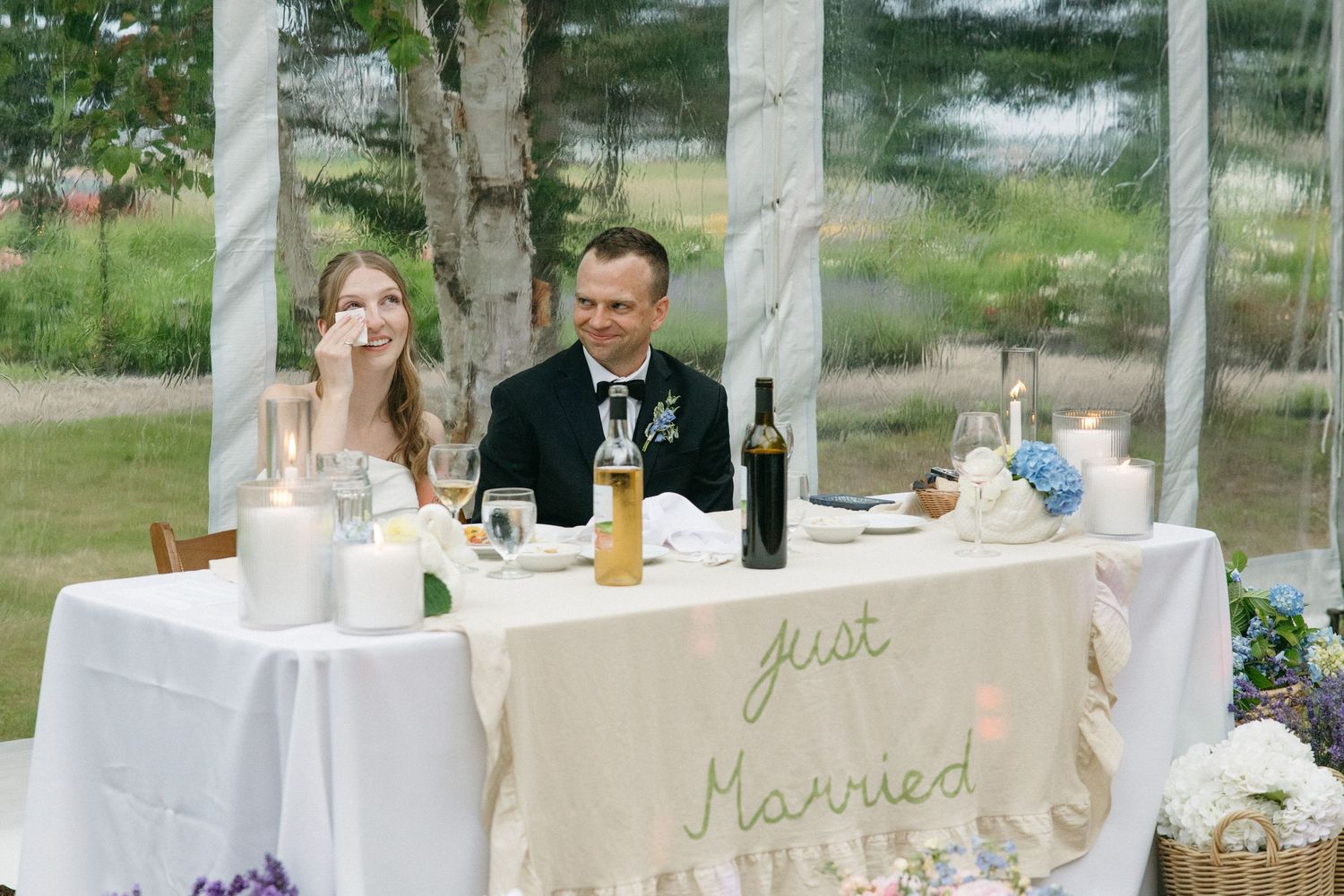 Newlyweds sit at sweetheart table with Just Married sign during wedding reception.