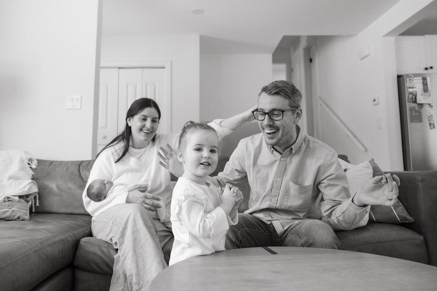 Monochrome series of family photos showing intimate moments of bonding and play on a couch.