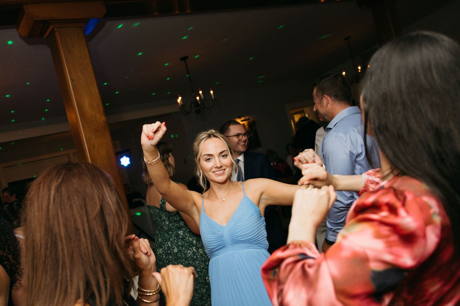 Woman in blue dress dancing joyfully at wedding reception celebration.