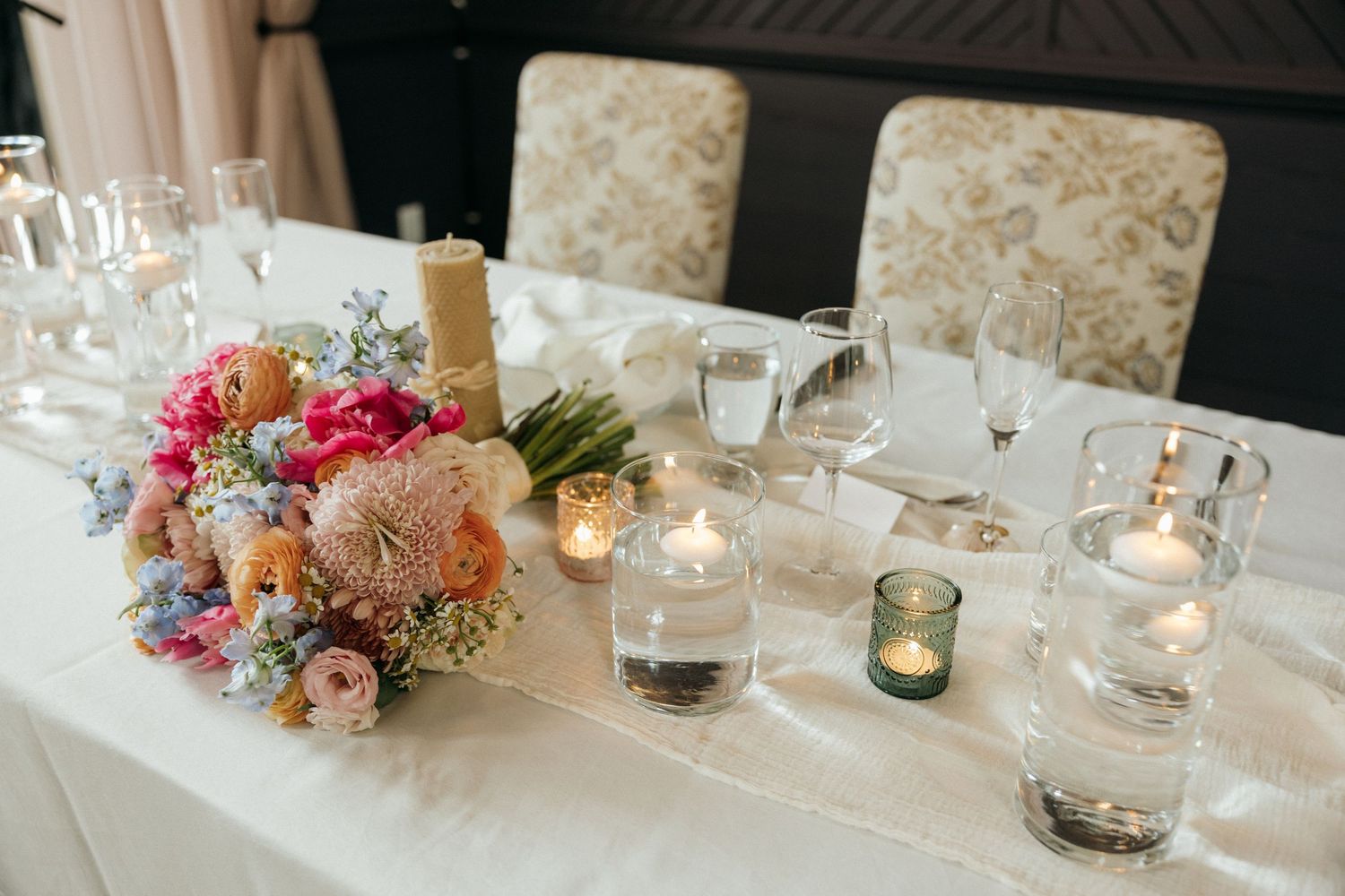 Wedding reception tables decorated with floral centerpieces and glowing candles.