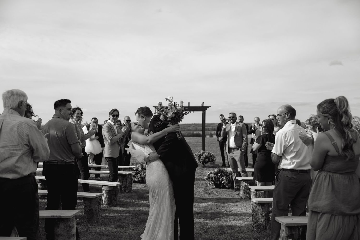 Guests seated in rows during an outdoor countryside wedding ceremony.