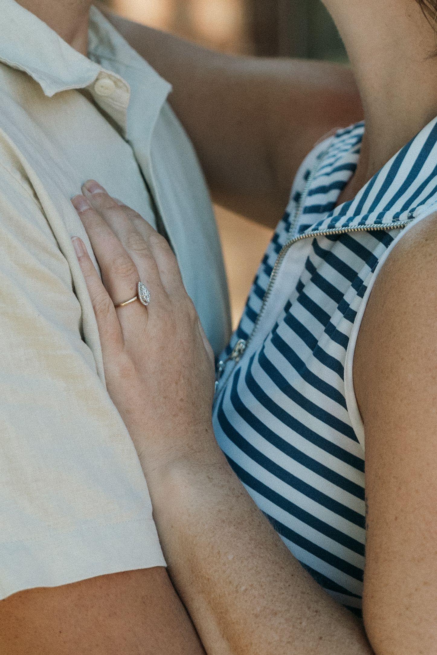 Close-up detail of hands resting on a striped fabric.