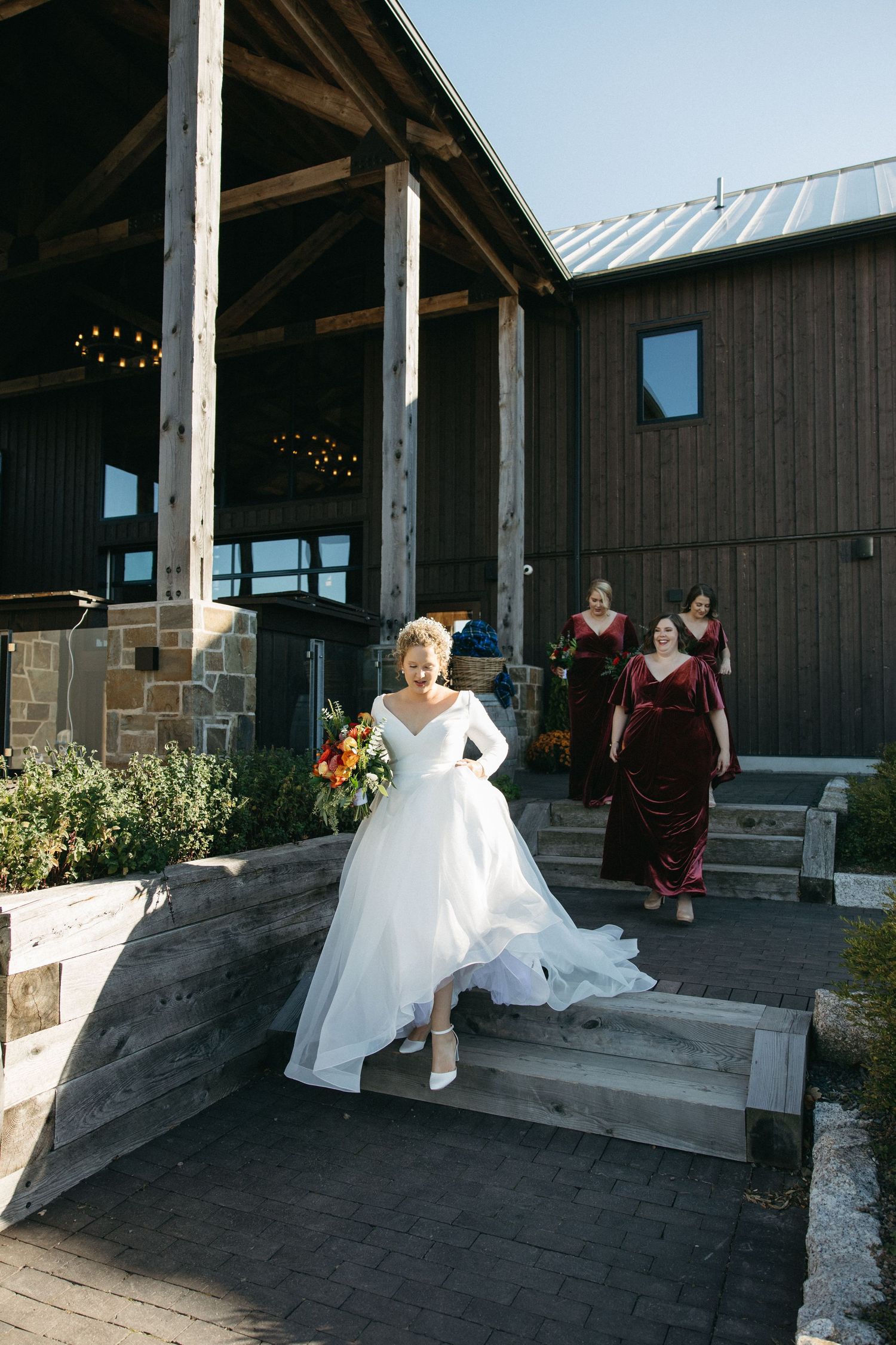 Wedding party walking outside a rustic wooden venue with white dresses.