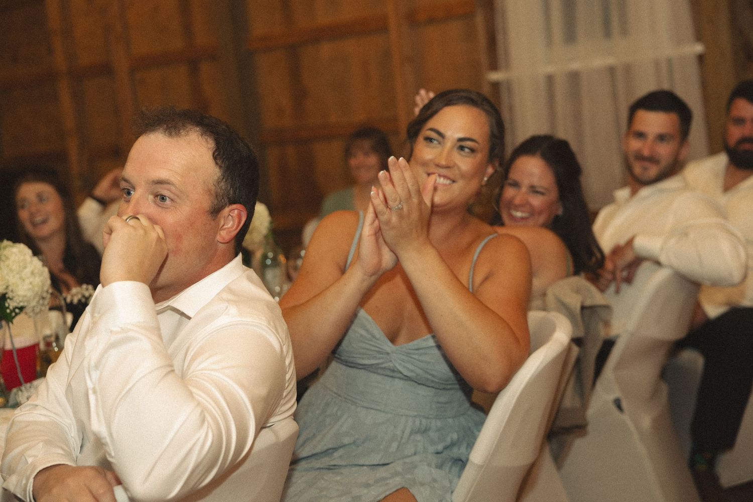 Wedding guests reacting emotionally during reception speeches.