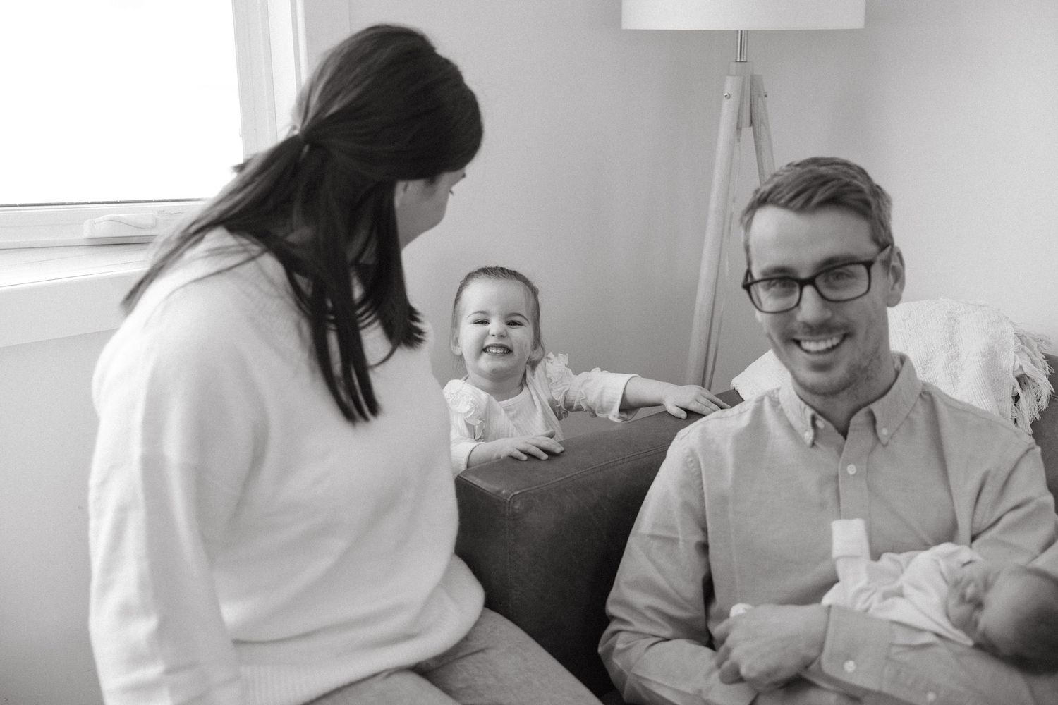 A candid black and white photo of a family sharing a joyful moment together on their couch.