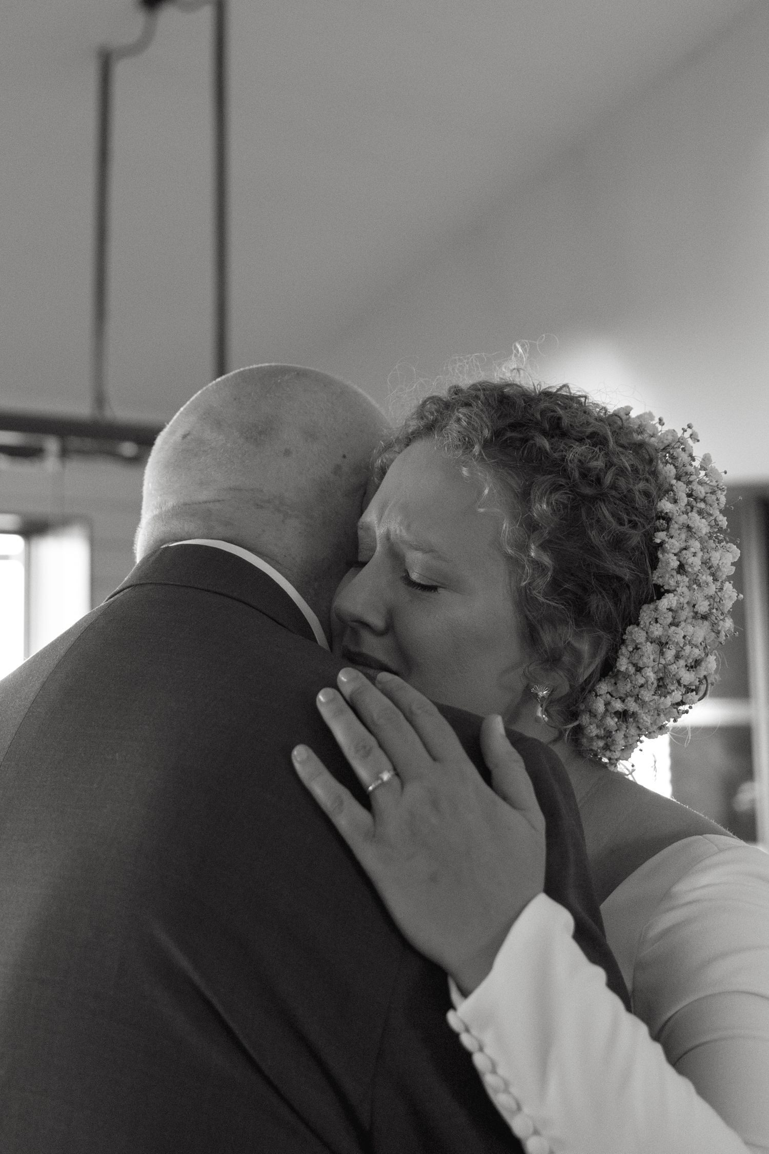 Black and white emotional moment captured during a wedding embrace.