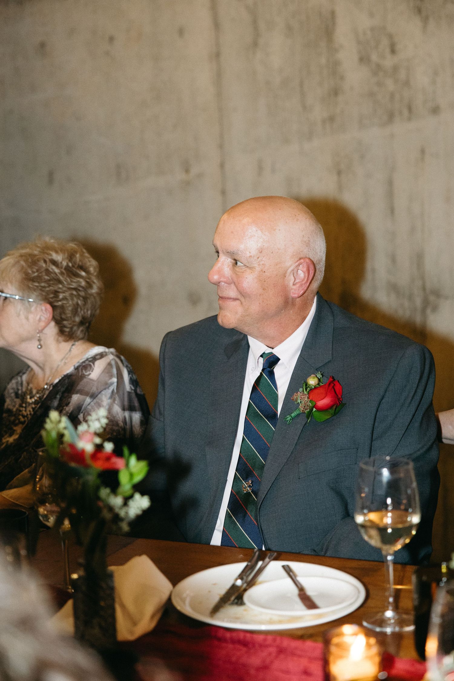 Formal dinner guest in suit with boutonniere enjoying conversation at wine cellar table.