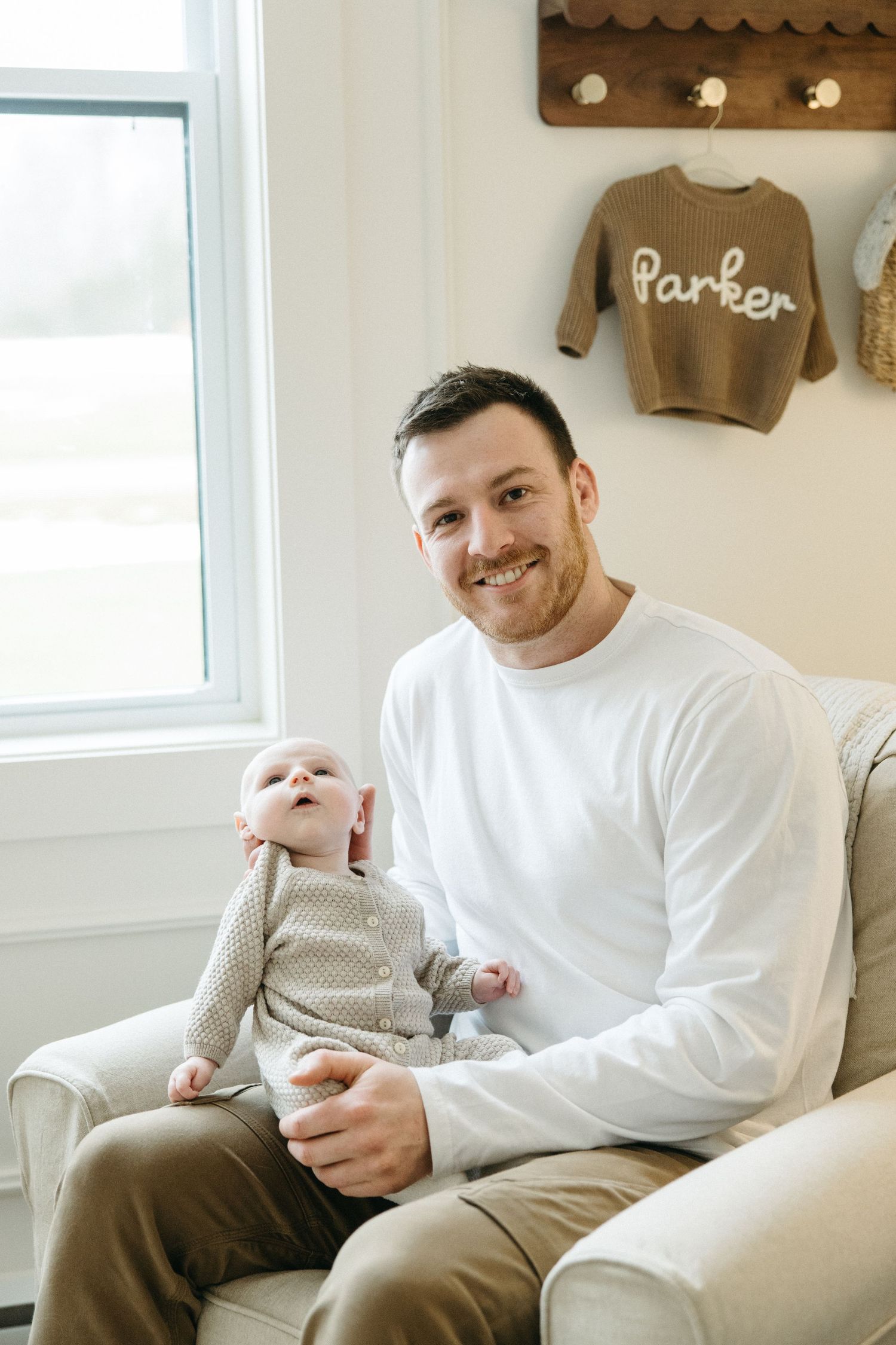 Cozy living room scene with baby in knit sweater and wall decor.
