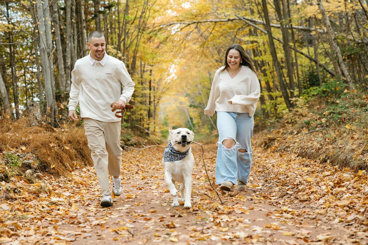Family walking together on a leaf-covered forest path in fall.