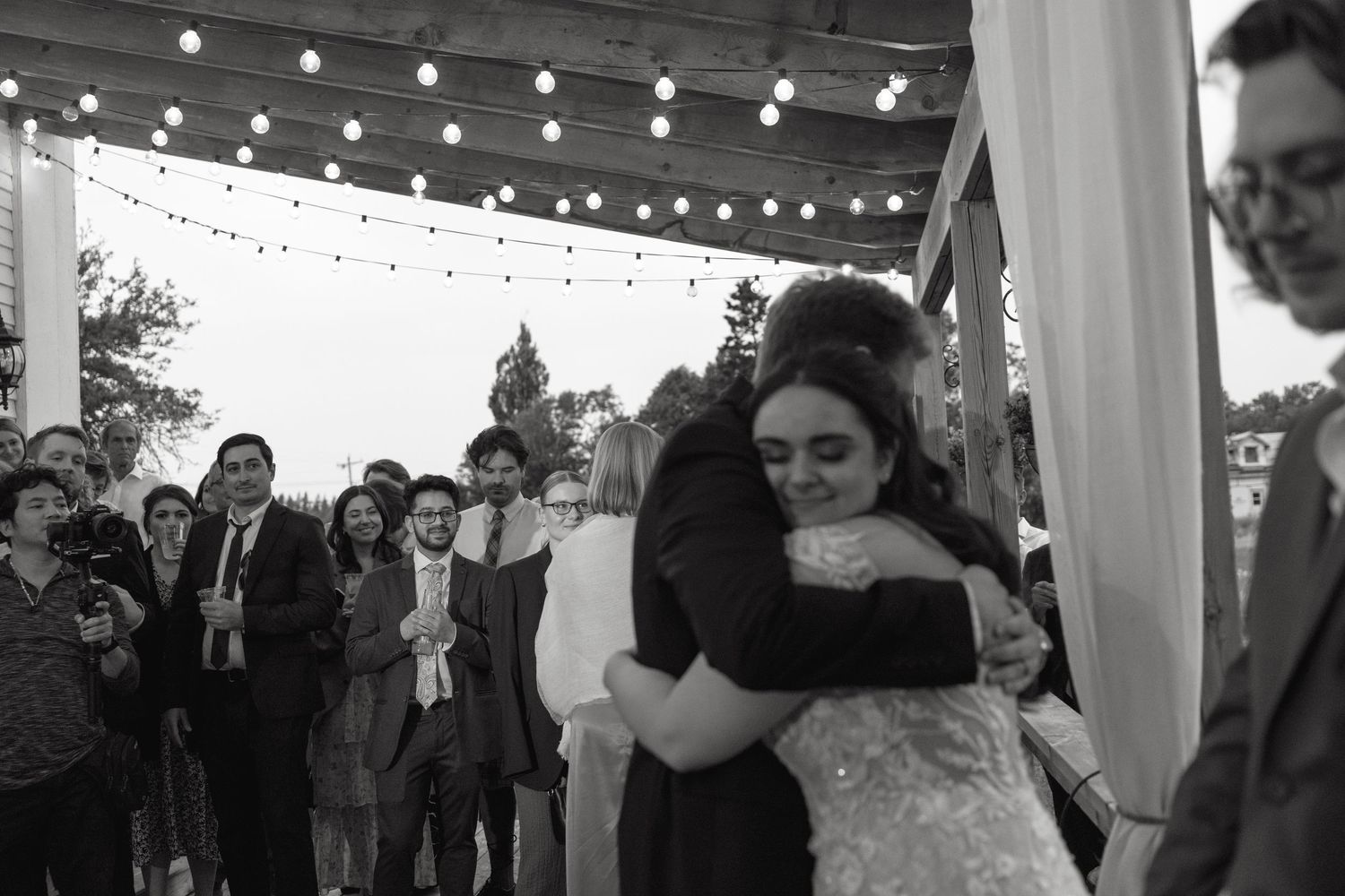 An emotional embrace shared during a wedding reception under string lights.