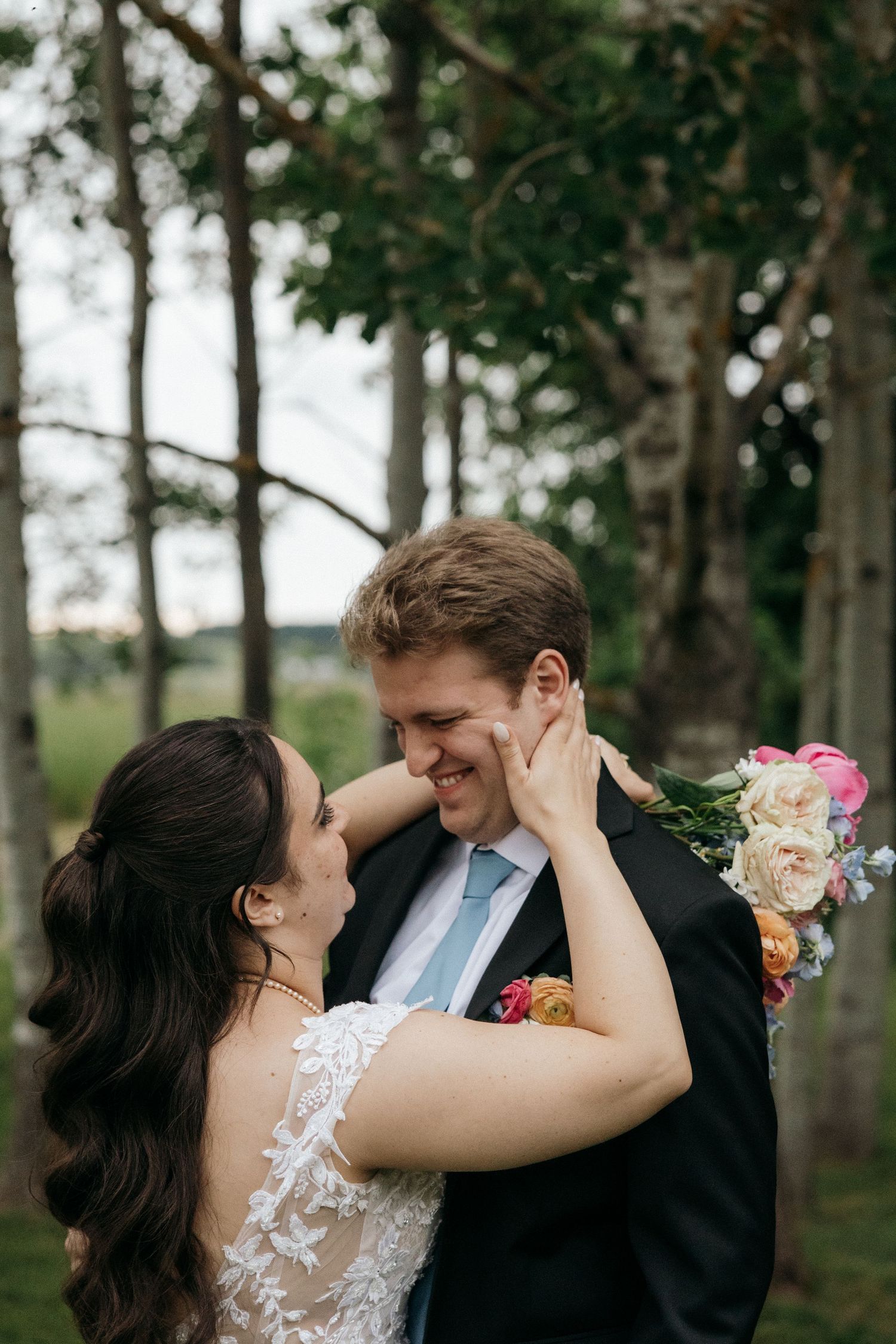 Candid wedding portraits of a couple sharing intimate moments among trees.
