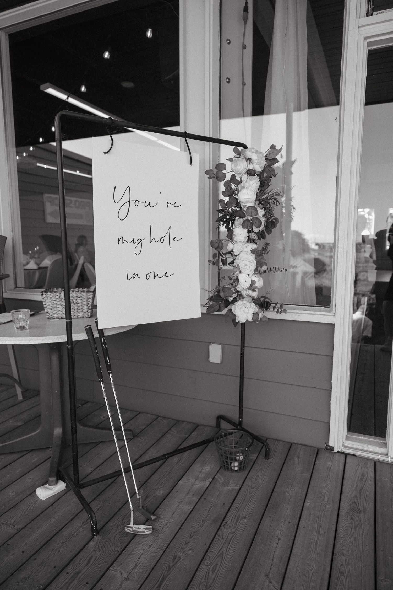Black and white photo of romantic signs displayed on wooden deck with floral arrangements.