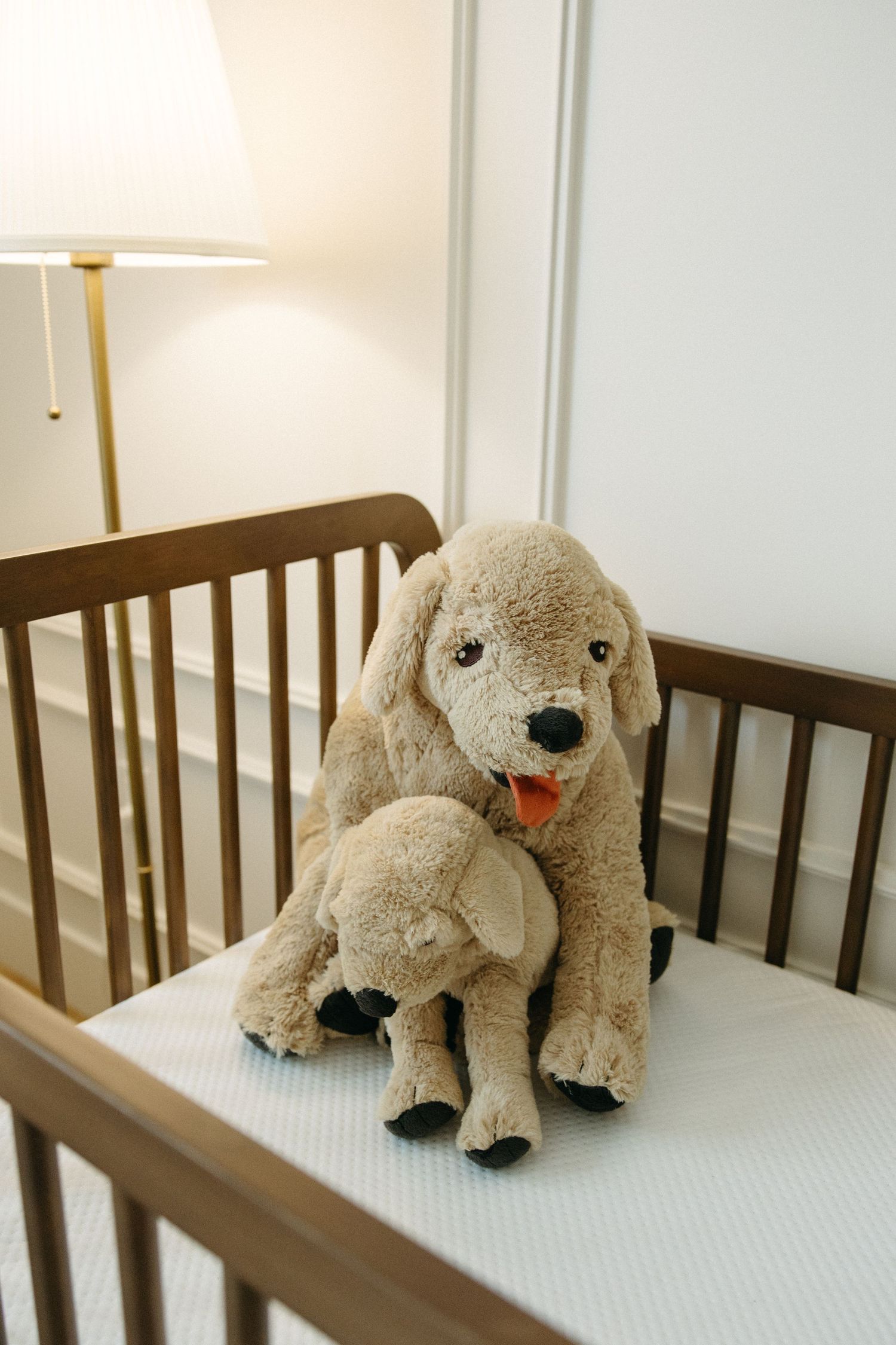 Plush puppy stuffed animal displayed on white mattress in nursery setting.