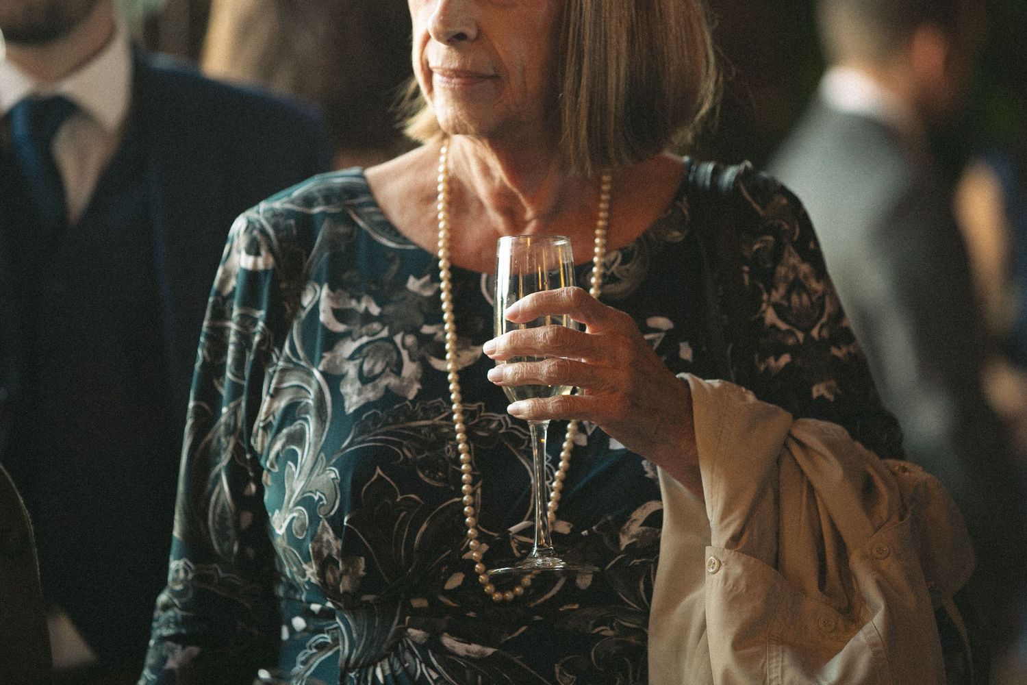 Elegant guest in a patterned dress holding a champagne glass at an evening event.