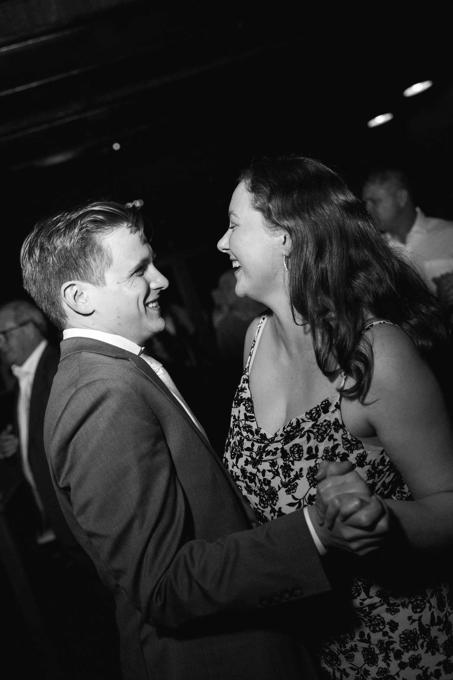 Two people dancing closely together at a dimly lit wedding reception.