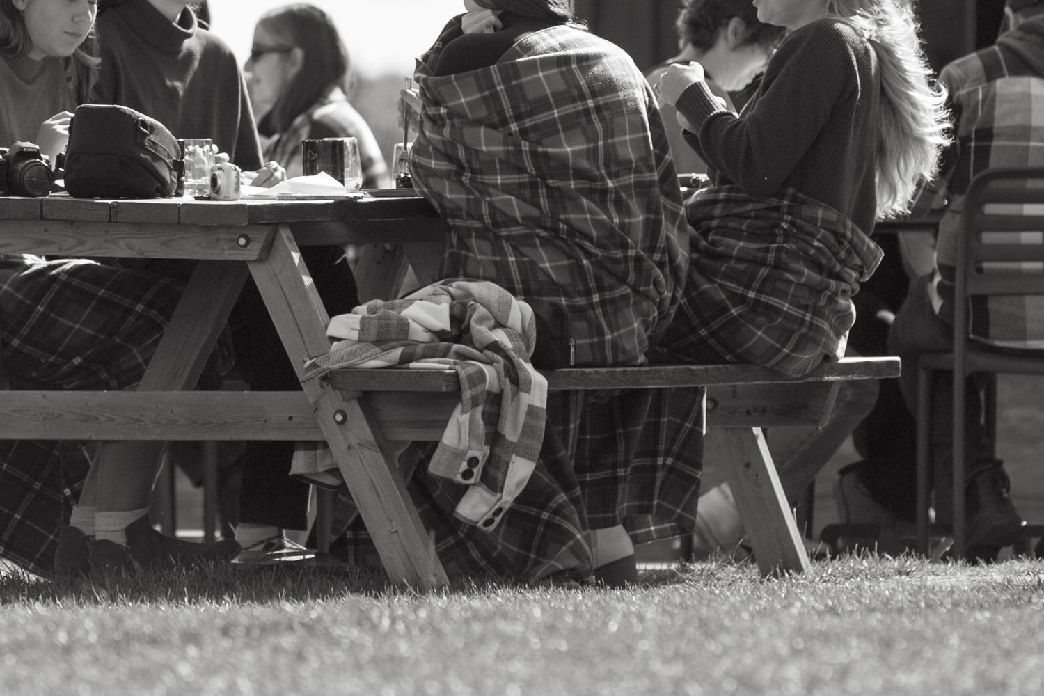 People gathered at outdoor picnic tables in black and white photography.