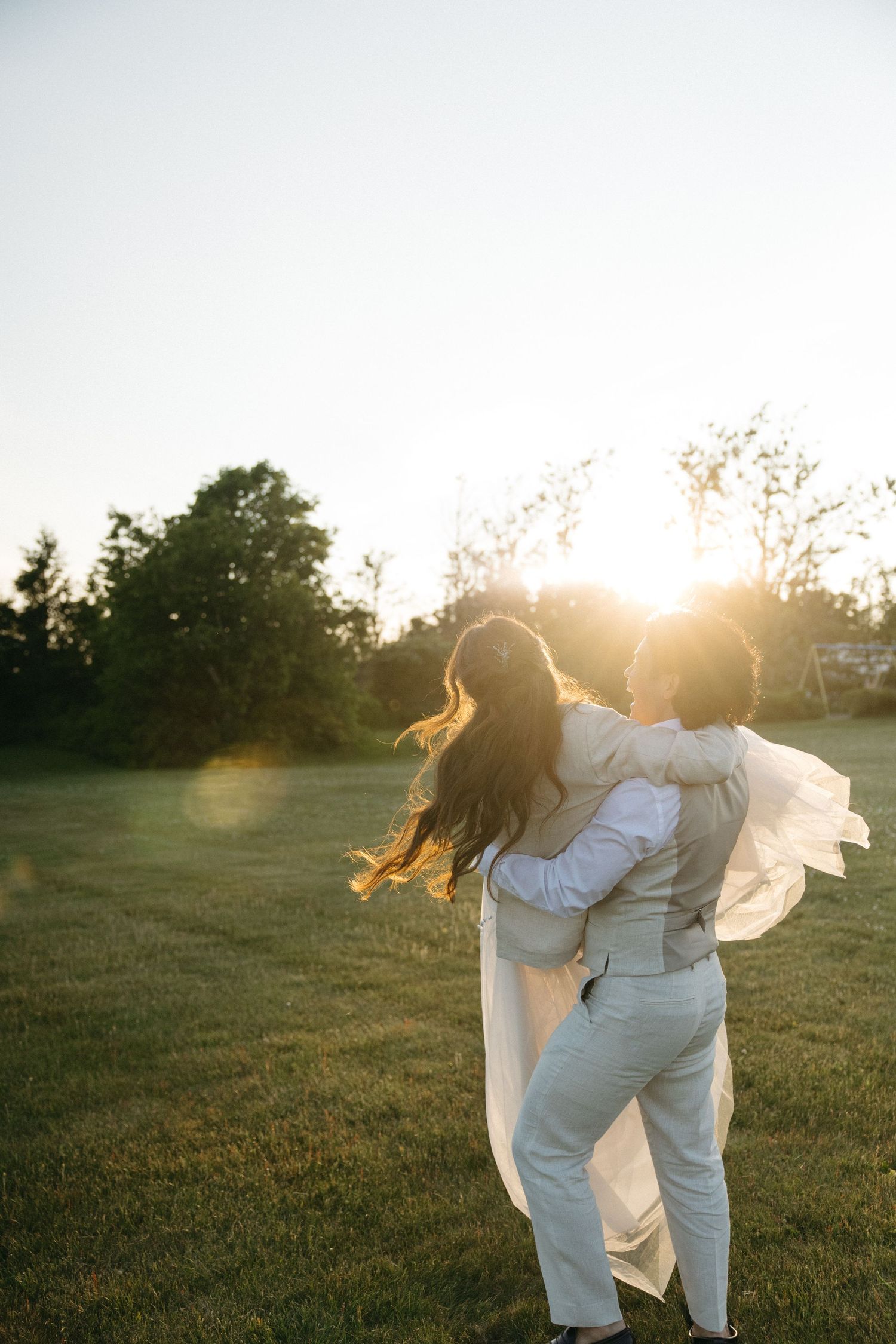 A figure in white dances joyfully in a sunlit field at golden hour.