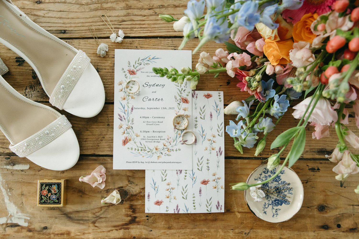 Wedding stationery and floral decorations arranged on rustic wooden table.
