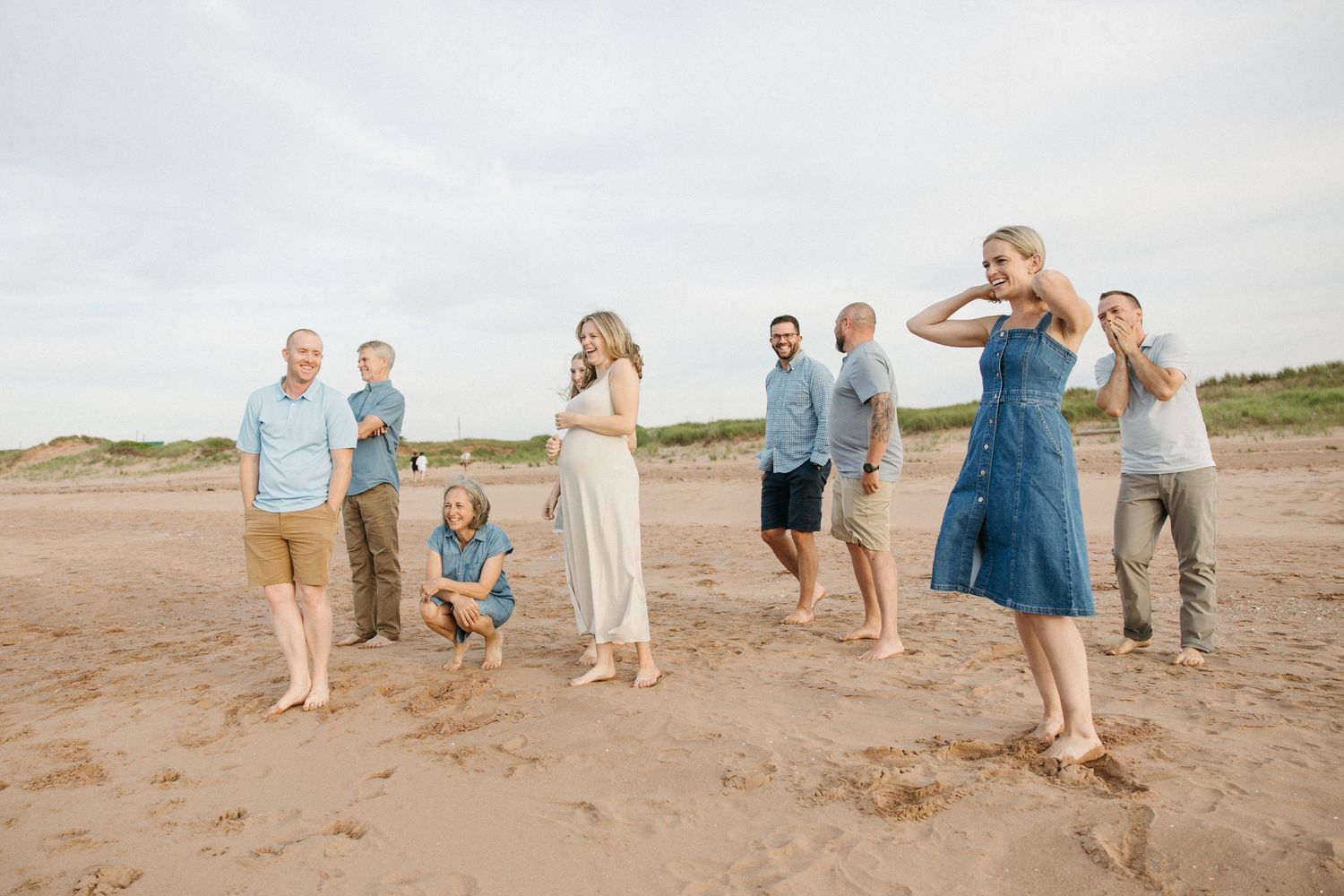 Large family group enjoying a casual beach gathering on sandy shores, dressed in casual summer attire.