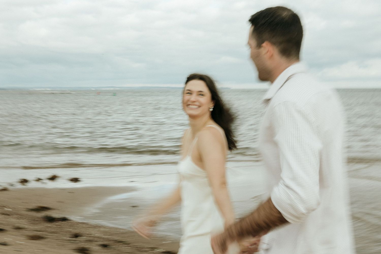 A joyful dance sequence captured on a serene beach with ocean waves in the background.