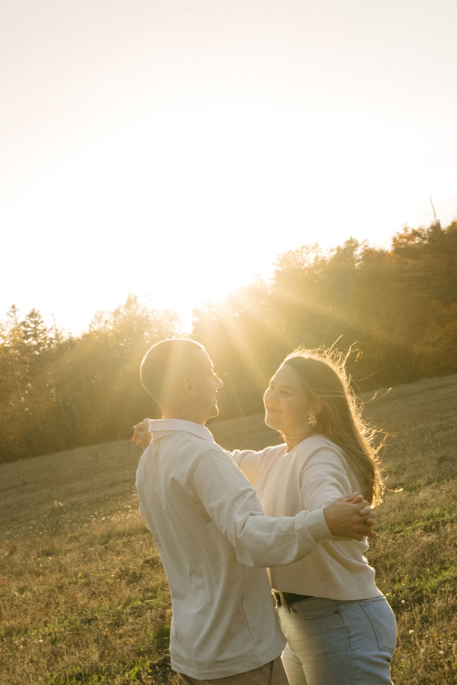 People dancing together in a sunlit field at sunset.