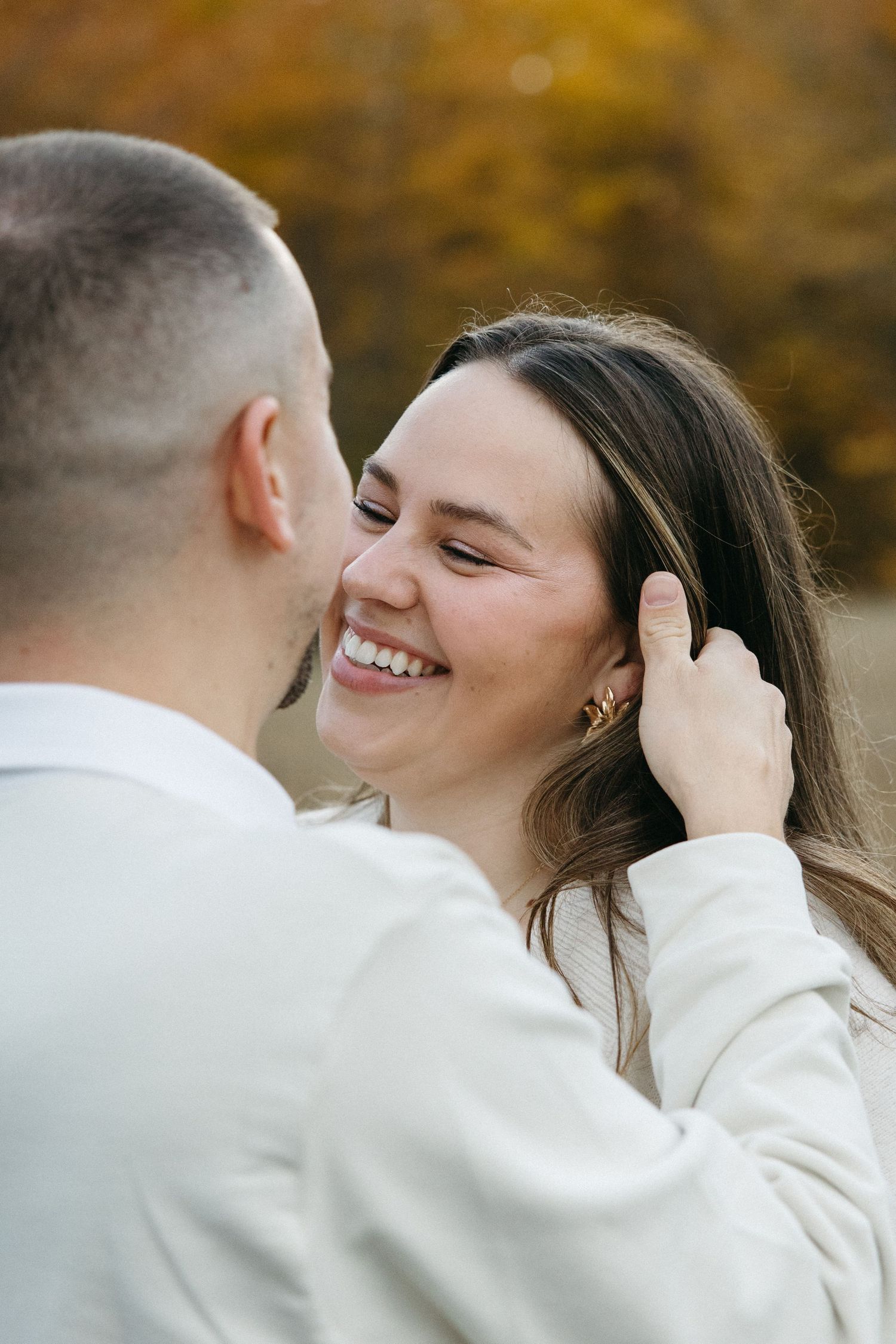 A romantic moment captured between a couple sharing laughter in an autumn setting.