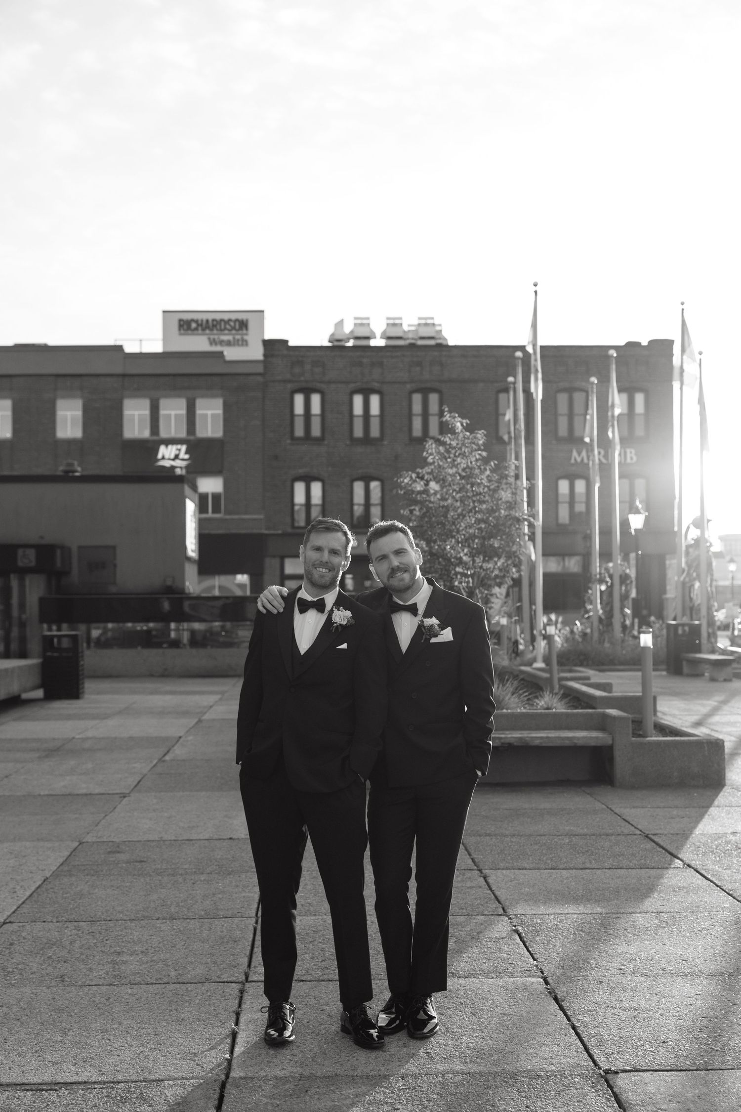 Black and white photo of formally dressed people walking along an urban sidewalk.