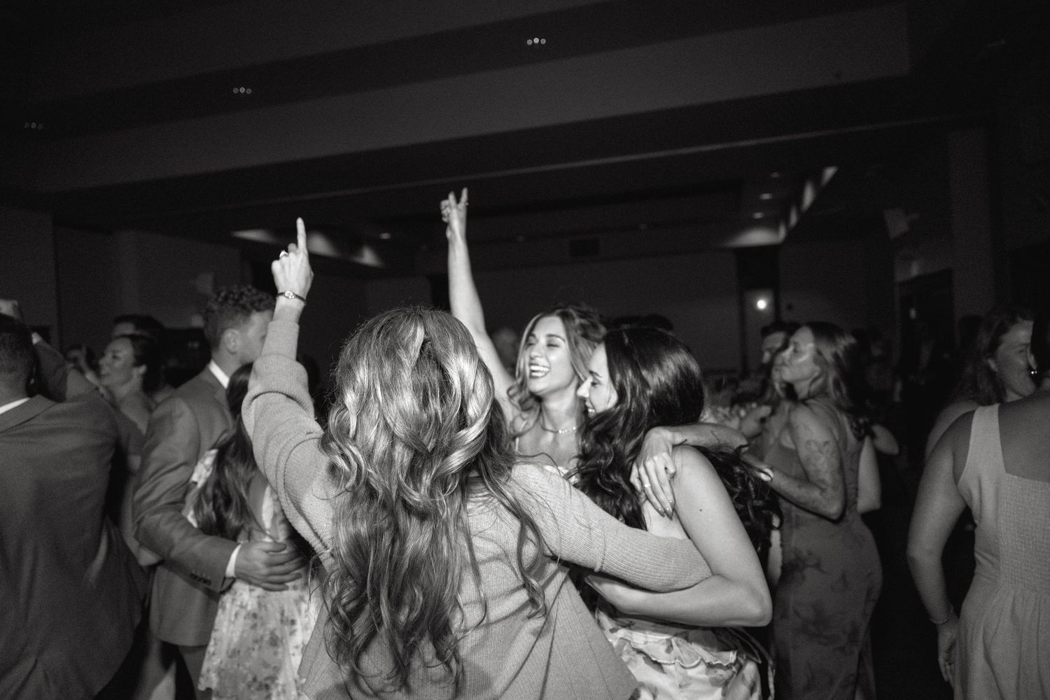 Silhouettes of people dancing and celebrating at a dark party venue with hands in the air.