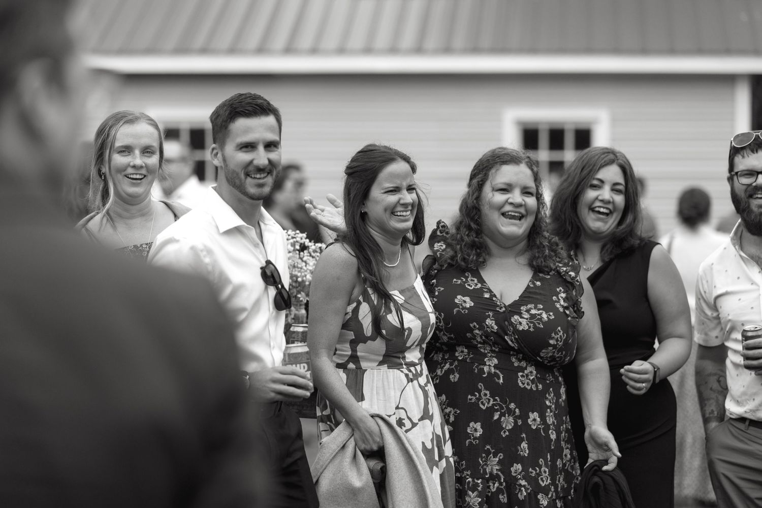 Wedding guests laugh and smile during an outdoor reception celebration.