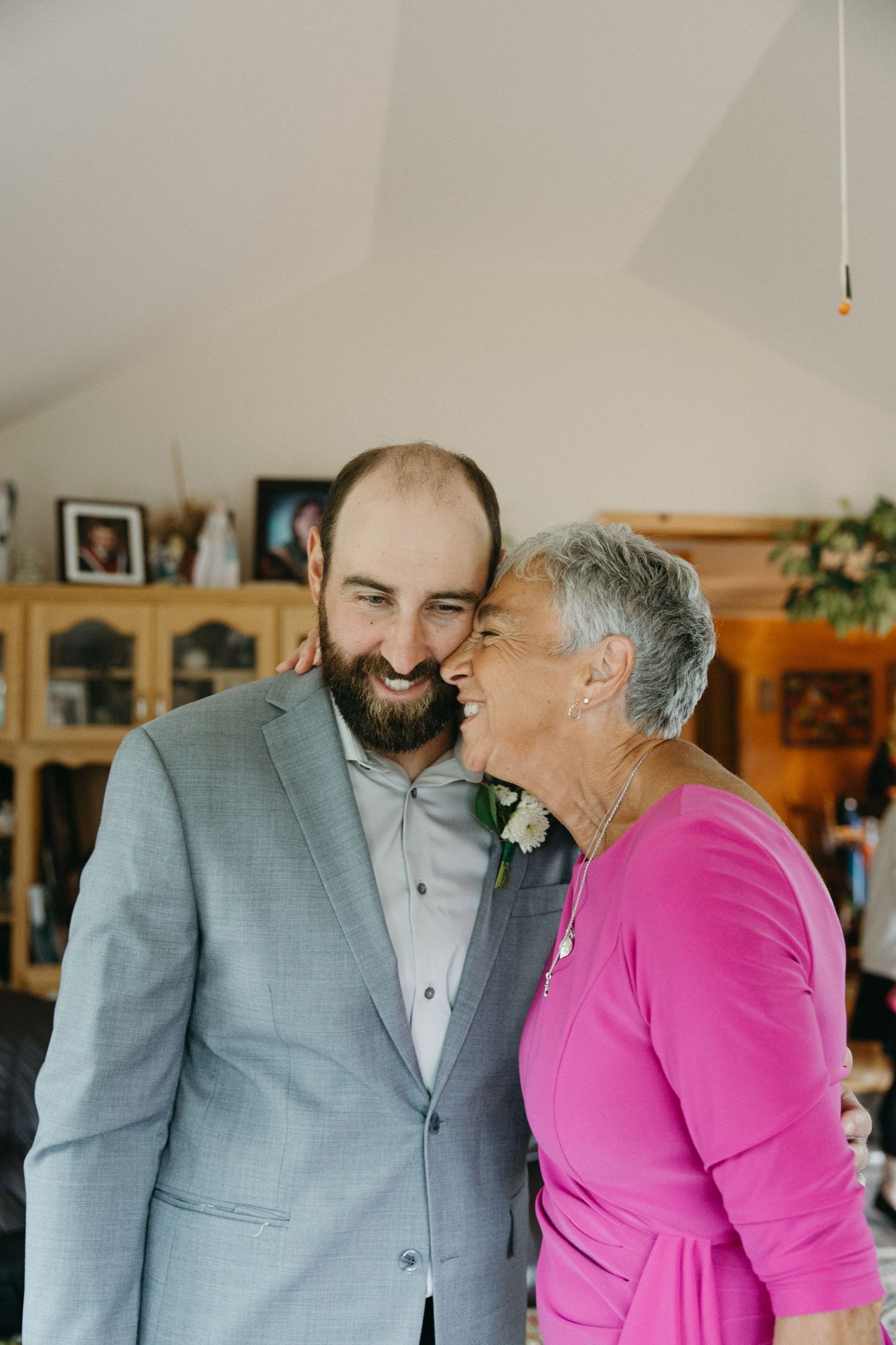 Two people sharing a joyful moment during wedding preparations in a home setting.