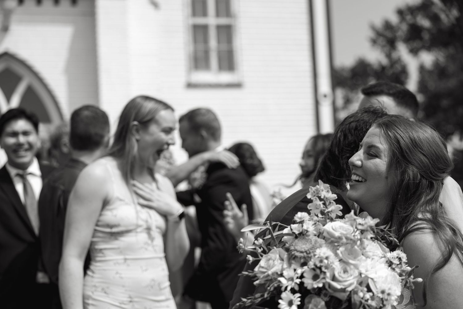 Wedding guests share emotional reactions during outdoor ceremony.