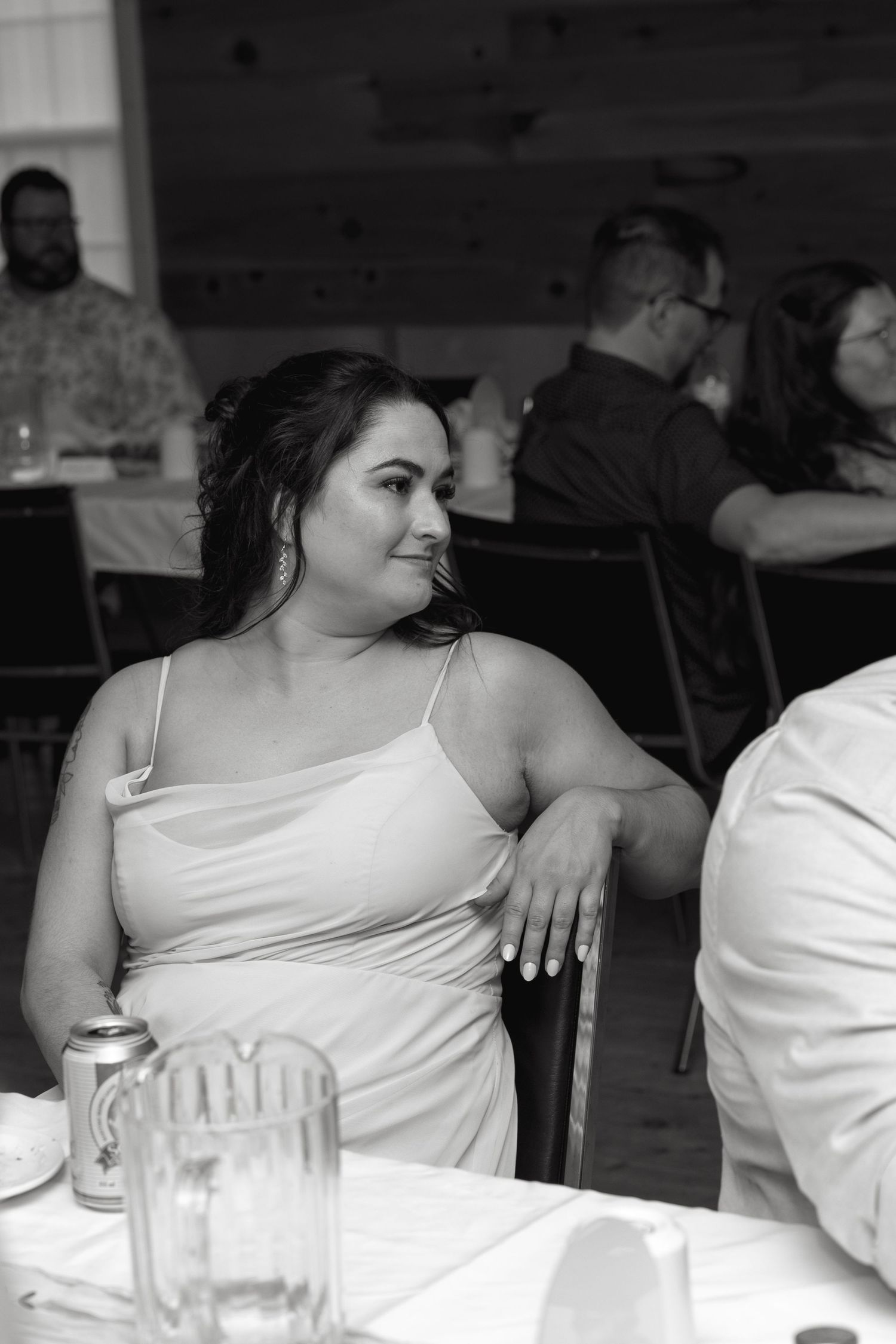 Wedding guests seated at reception tables with white linens and glassware.