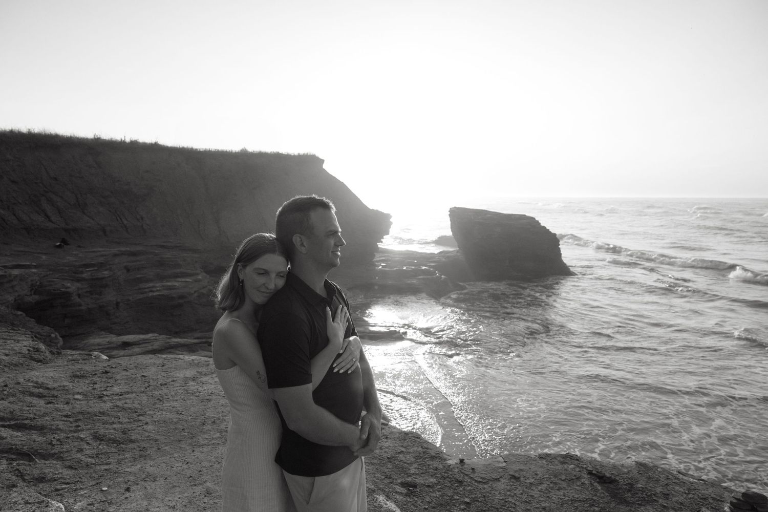 Dramatic black and white coastal landscape with rocky cliffs and crashing waves.