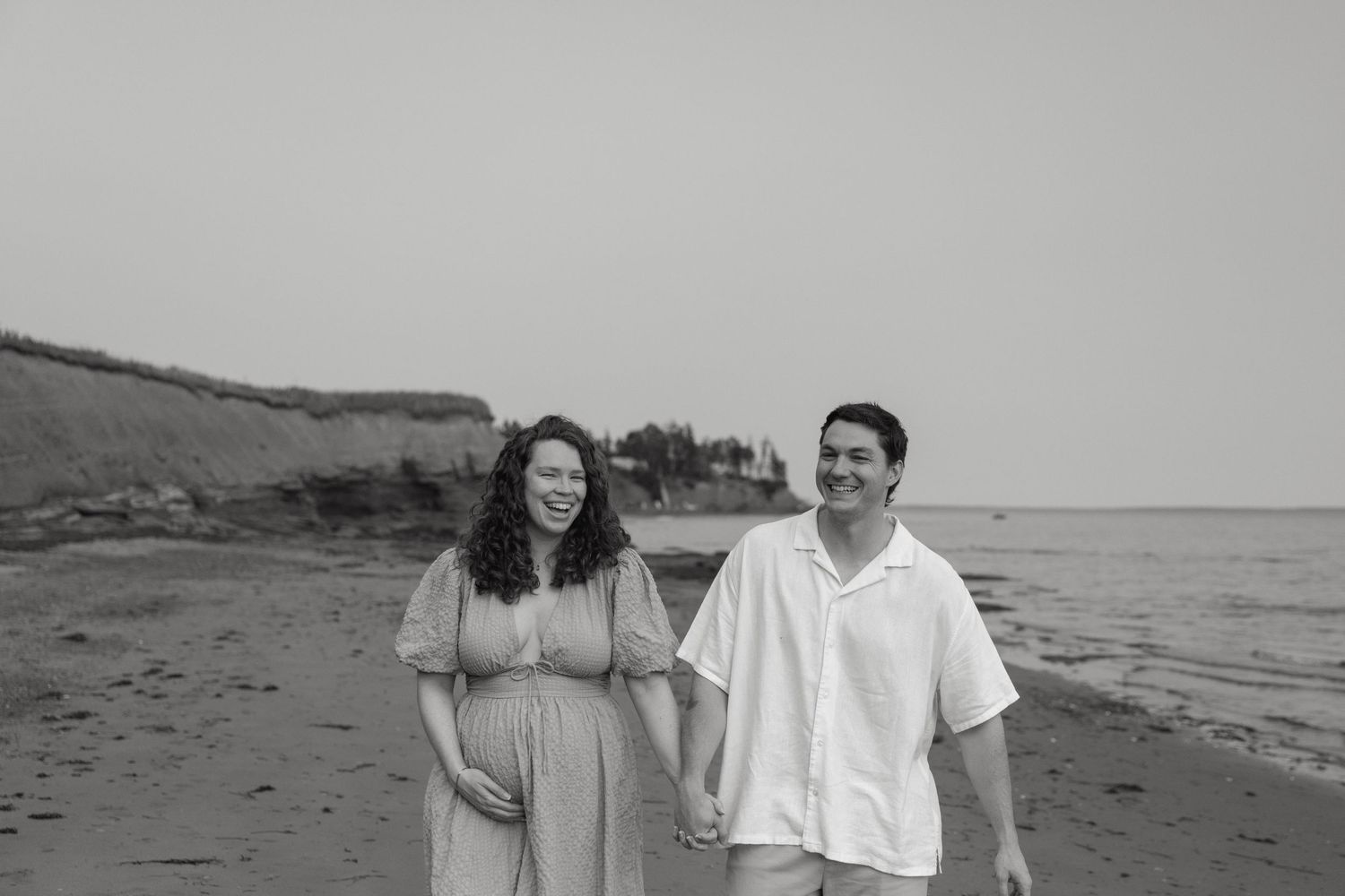 Couple walking together on beach path in black and white.