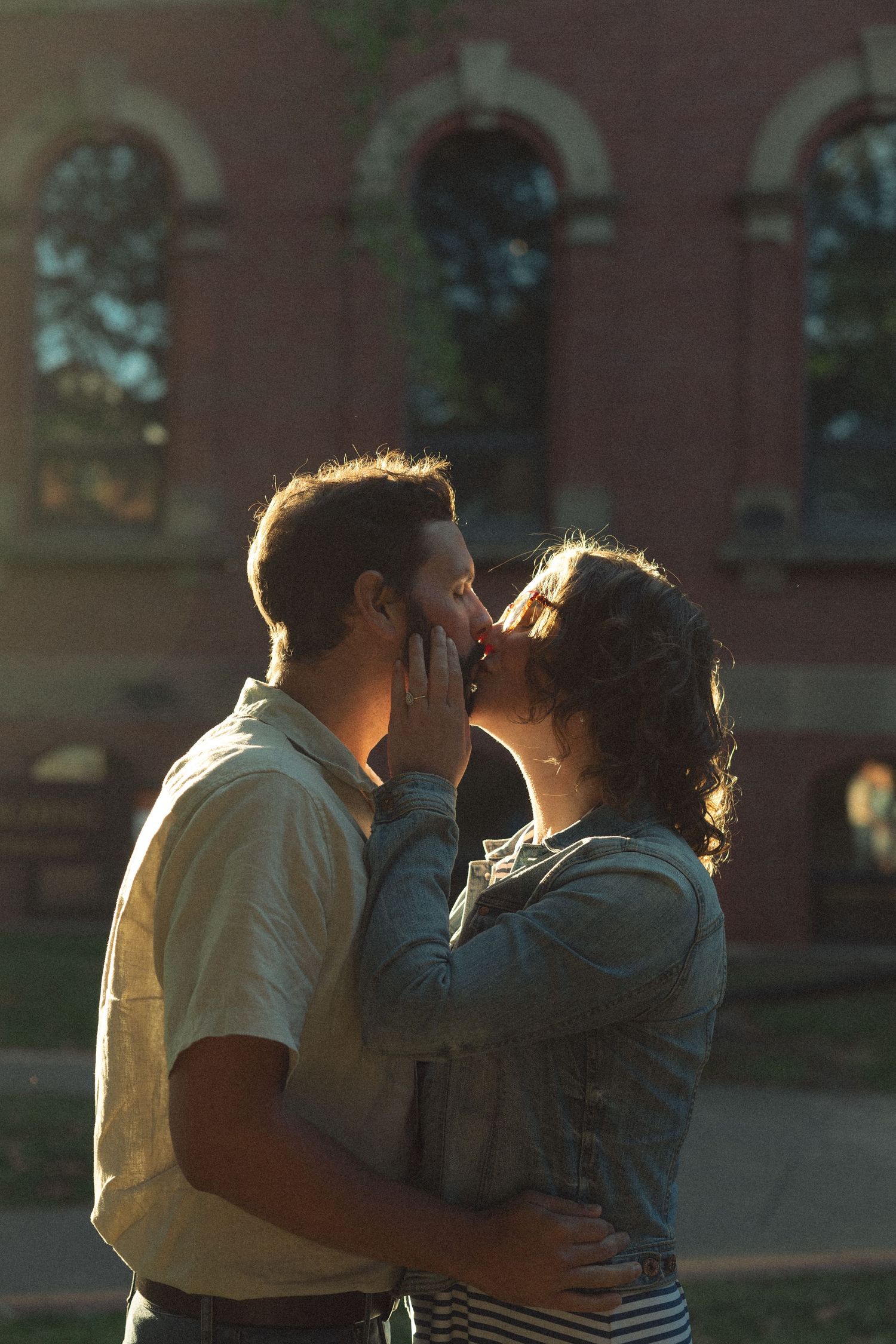 A couple shares an intimate sunset moment against a warm backlit glow.