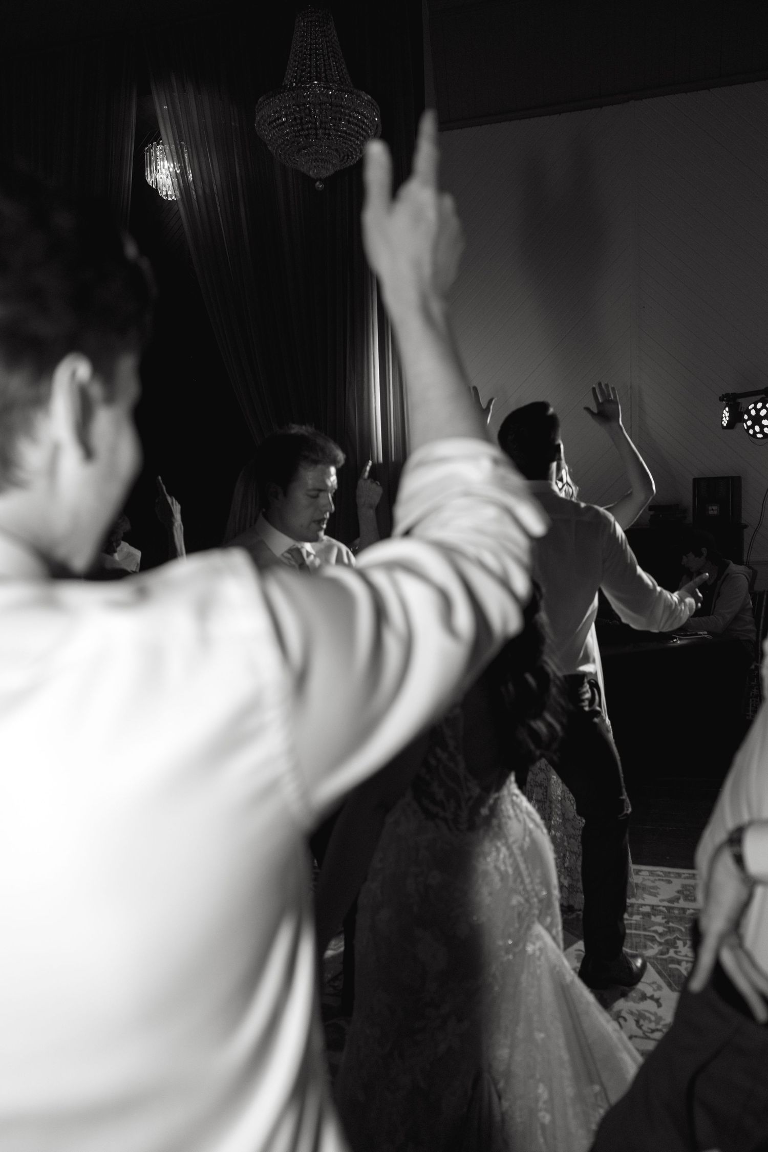 Silhouettes of people dancing with hands raised at a wedding reception.