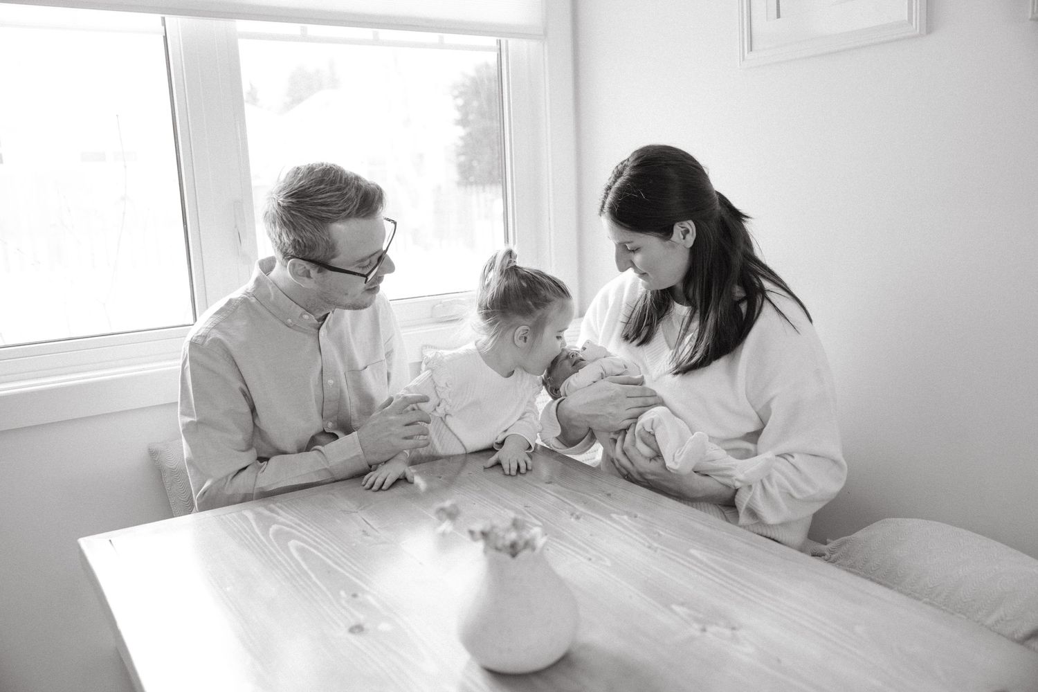 Candid black and white photo of family members relaxing together in a cozy home setting.