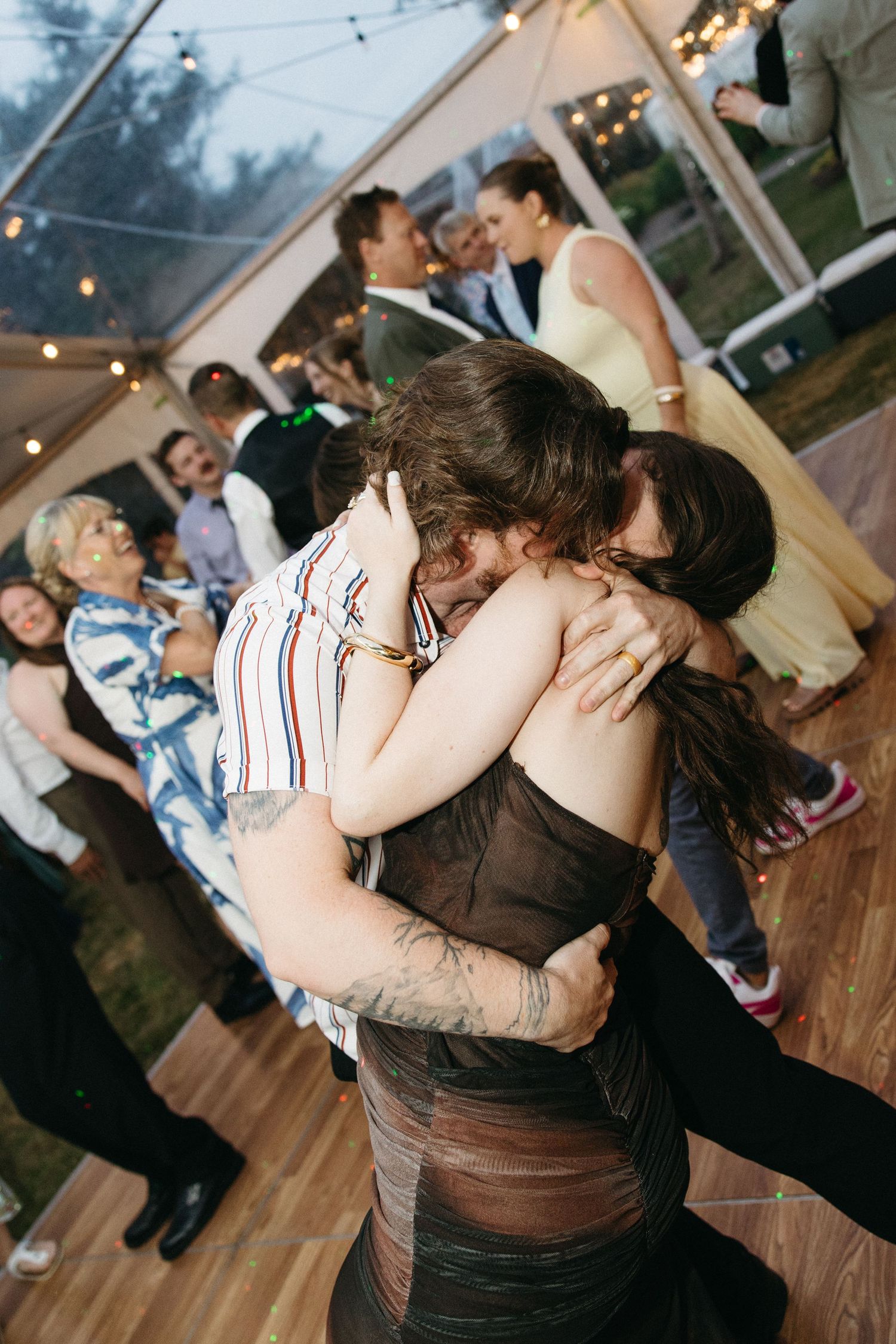 Two guests sharing an emotional hug on the dance floor at a wedding reception.