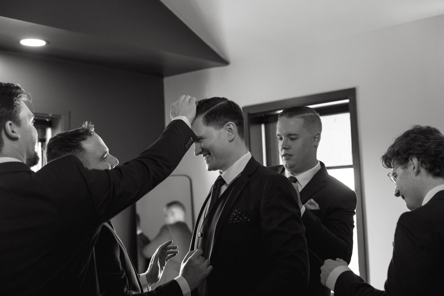 Wedding party members prepare in a bright room with modern lighting.