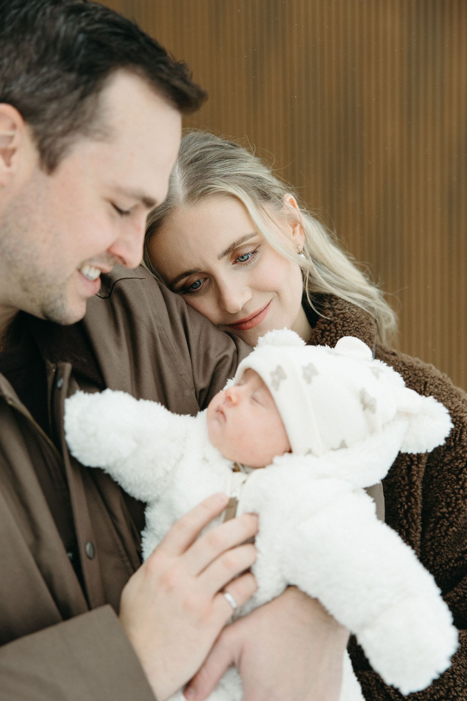 An intimate family portrait showing tender moments with a newborn in white.